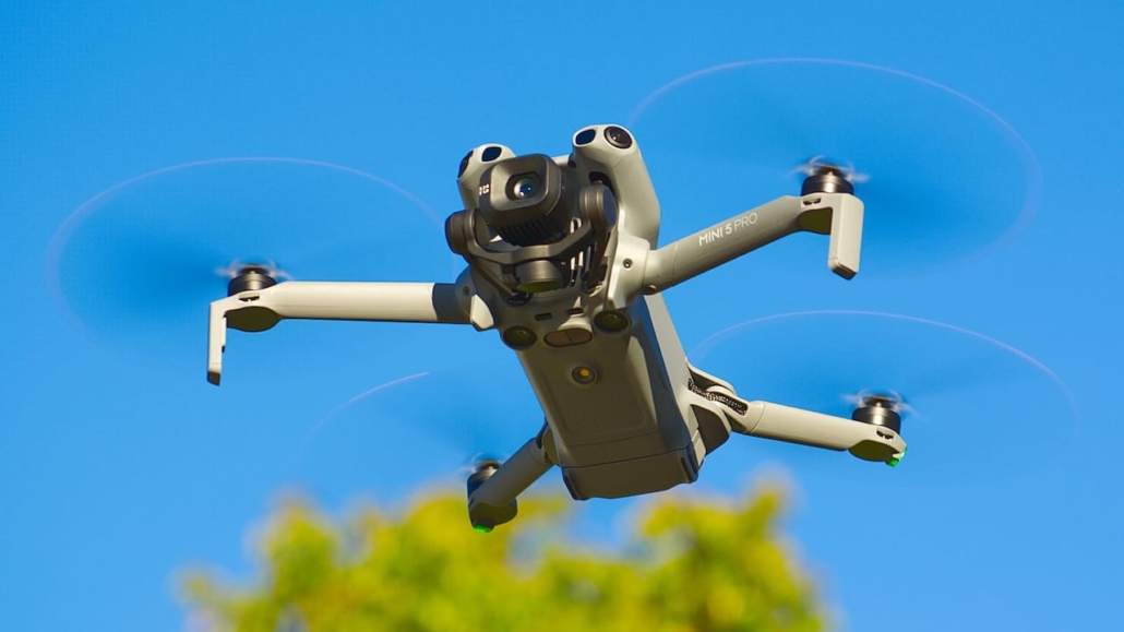 Aerial photography drone in flight against a clear blue sky, used for real estate media.